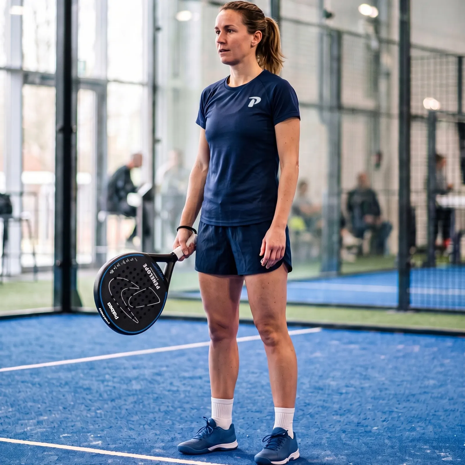 Woman player on an indoor padel court with the PENELOPE racket